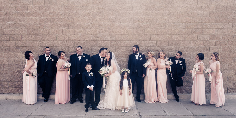 Wedding Bridal Party Uniquely posed in front of a brick wall in pink dresses